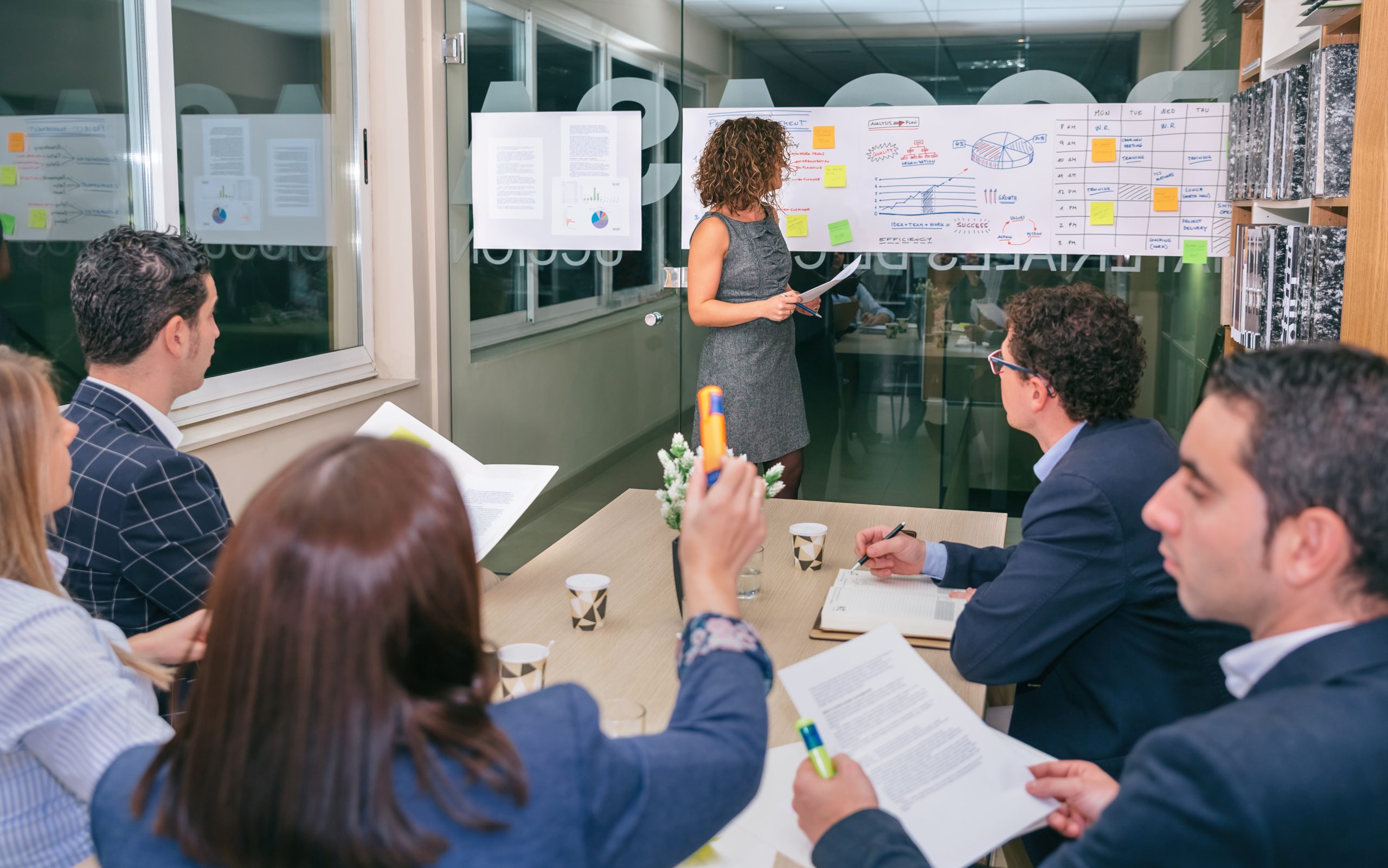 Female coach looking business graph while businesswoman having question